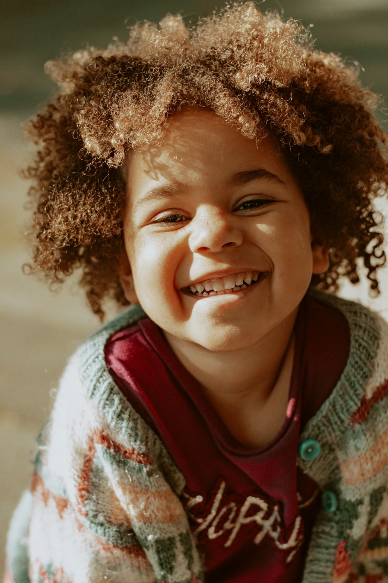 A smiling child in a knitted jumper