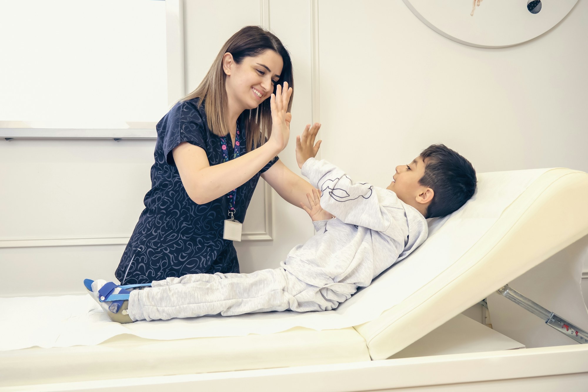 A nurse high-fives a young boy on a hospital bed