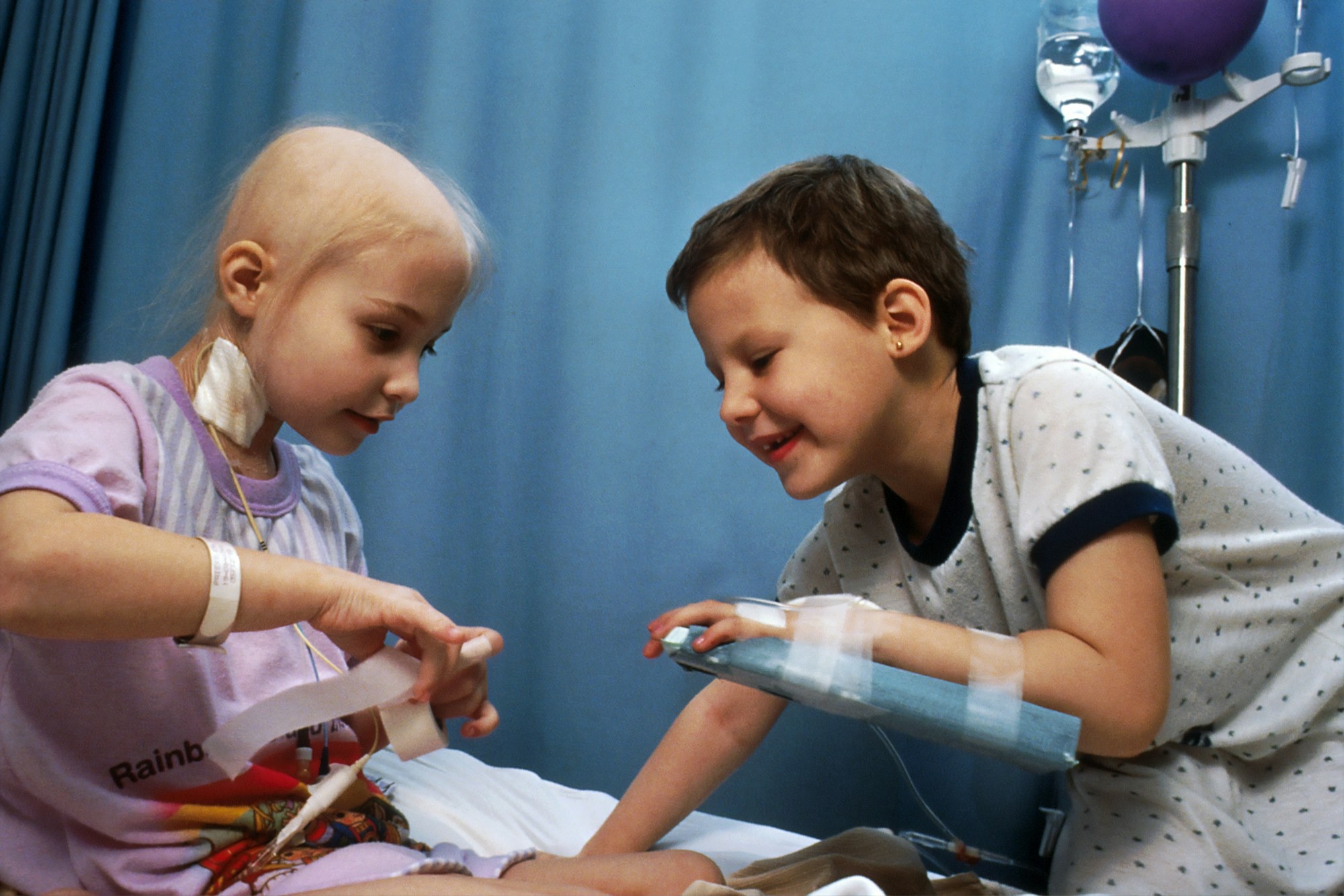 Two children laughing together on a hospital bed